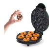 Hand Holding a Sprinkled Mini Donut Above a Six-donut Maker with the Lid Open.