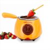 Orange Chocolate Fondue Pot with Melted Chocolate and a Strawberry on a Skewer Dipping into It, Surrounded by Strawberries on the Side.
